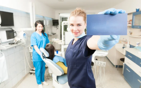 Bela dentista com cand de negócios em sua mão — Fotografia de Stock