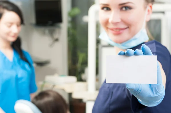Woman dentist holding a blank white business card — Stok fotoğraf