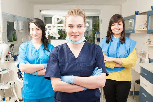 Dentist with crossed arms with patient and assistant behind her — Stock Photo, Image