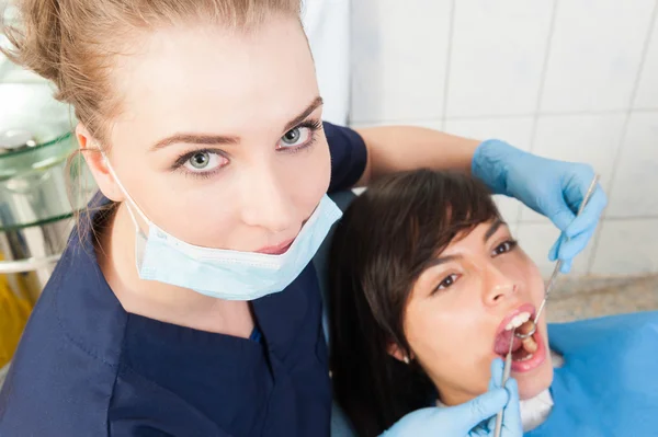 Mujer hermosa dentista examinando dientes de paciente hembra — Foto de Stock