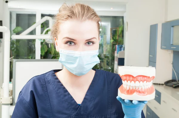 Retrato de una hermosa dentista usando máscara y sosteniendo ja ja — Foto de Stock