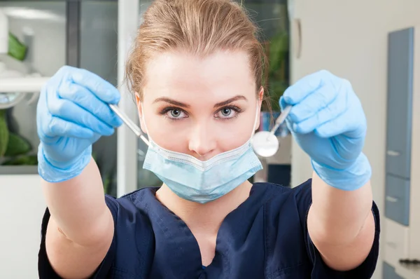 Ελκυστική γυναίκα οδοντίατρος φορώντας μάσκα και κρατώντας Οδοντιατρικά εργαλεία — Φωτογραφία Αρχείου