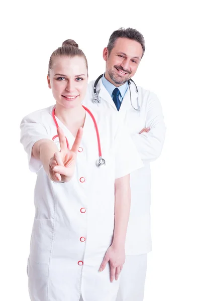 Zufriedene Ärzte lächeln freundlich und zeigen Frieden oder Sieg — Stockfoto