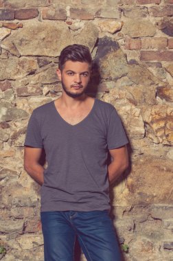 Genç yakışıklı sakallı hippi adam taş duvara yakın ayakta