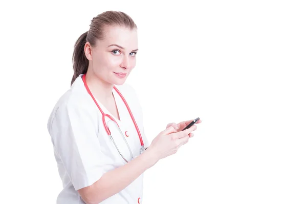Ärztin benutzt Smartphone und lächelt freundlich — Stockfoto