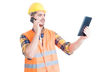 Yakışıklı mühendis akıllı telefonda konuşuyor ve tablet kullanıyor 