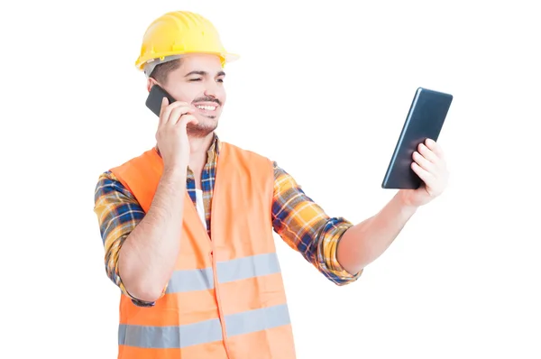 Constructeur masculin avec tablette moderne utilisant un téléphone portable et souriant — Photo