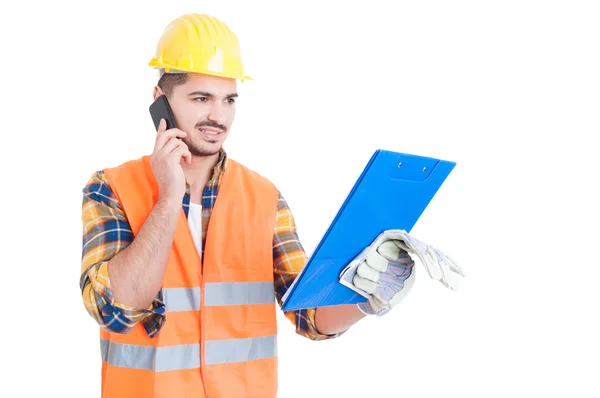 Joven ingeniero con casco con portapapeles llamando al celular —  Fotos de Stock