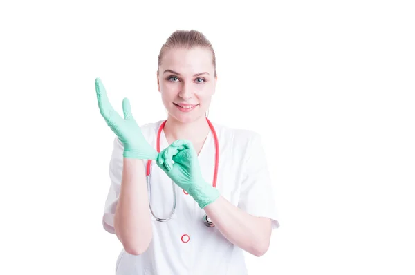 Young female doctor putting on sterile latex gloves — Stockfoto