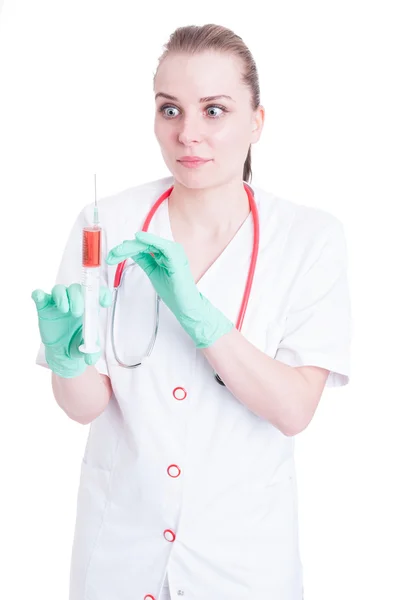 Scared woman doctor looking panicked to a syringe with needle — Stock Photo, Image