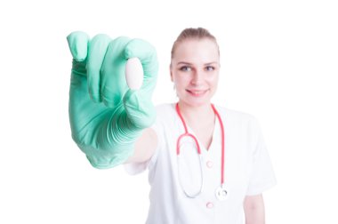 Gülümseyen ve bir hap yakın çekim içinde tutan çekici kadın doktor