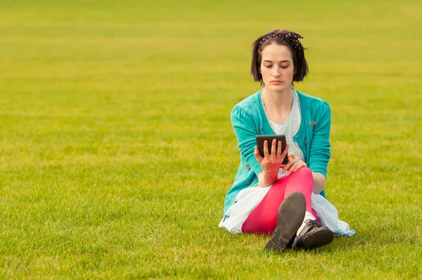 Jovem mulher usando seu tablet enquanto relaxa ao ar livre — Fotografia de Stock