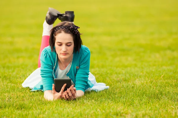 Привлекательная женщина с планшетом на открытом воздухе, сидя на траве — стоковое фото