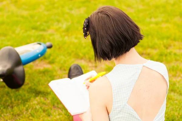 Primo piano di giovane donna indietro con bicicletta e un libro — Foto Stock