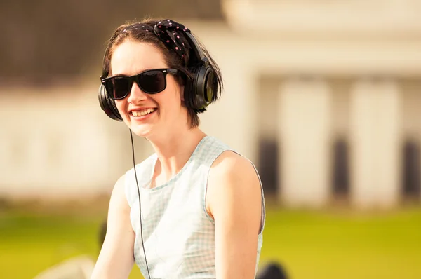 Dama młody wesoły hipster słuchanie muzyki w parku — Zdjęcie stockowe