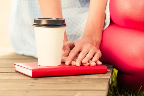 Крупный план кофе и женские руки держатся за книгу — стоковое фото