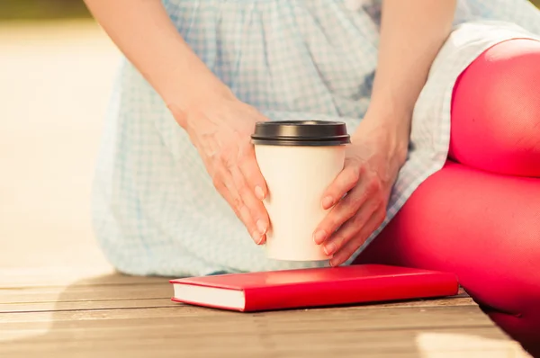 Крупный план книги и женских рук, держащих чашку кофе — стоковое фото