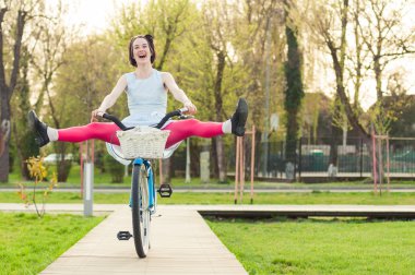 Bacaklarının havada ile neşeli kadın binicilik bisiklet