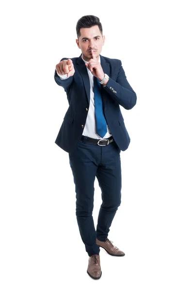 Uomo d'affari fare mantenere un gesto segreto in piedi su schienale bianco — Foto Stock