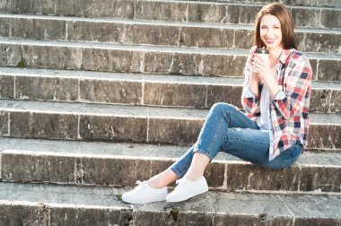 Kahve tutarak ve rahat kıyafetler giymiş gülümseyen kadın