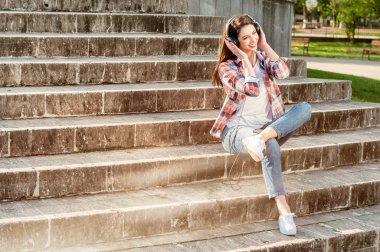 Güzel yenilikçi kulaklık ile şehir parkı merdivenlerde oturan