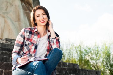 Neşeli genç kadın kişisel günlüğüne yazar