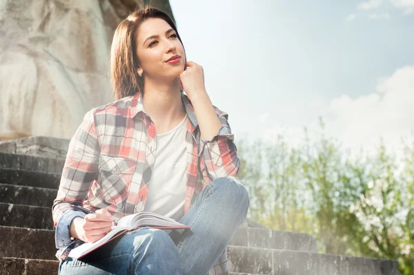 Hermosa joven escribe en el diario en el parque — Foto de Stock