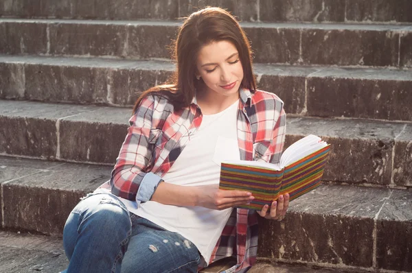 Joven hermosa chica leyendo un libro y descansando en las escaleras — Foto de Stock