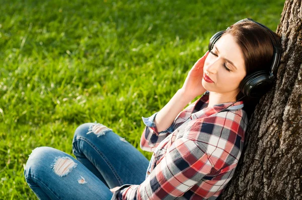 Beautiful relaxed woman enjoying music at headphones under old t — Stock Photo, Image