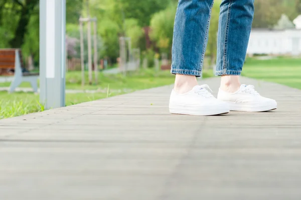 Woman feet with jeans and white casual shoes in closeup — Stock Photo, Image