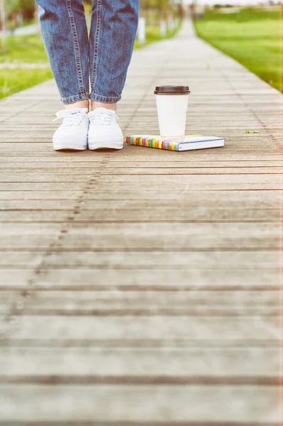 Hipster legs in close-up, a cup of coffee and book — Stock Photo, Image