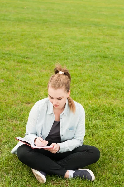 Jovem hipster mulher escrevendo em seu caderno no parque — Fotografia de Stock