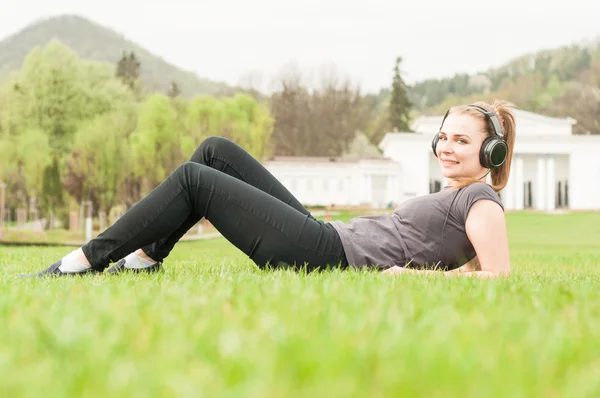 Šťastná žena se sluchátky naslouchající hudbě venku — Stock fotografie