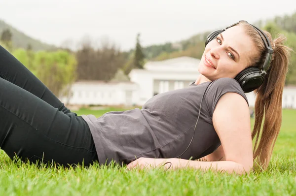 Happy woman relaxing and listening music in the park — Stock Photo, Image