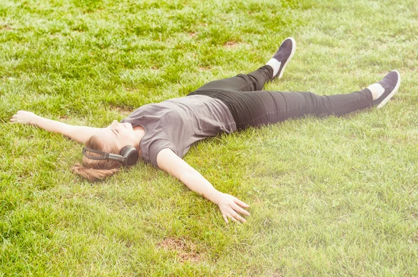 Young beautiful woman lying on grass with arms wide open — Stock Photo, Image