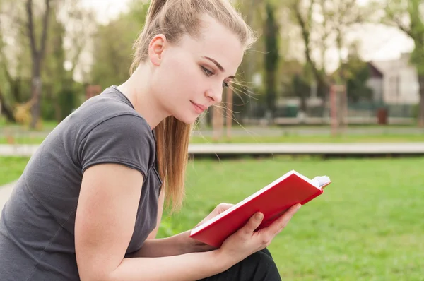 Attraente giovane donna che riposa e legge un libro — Foto Stock