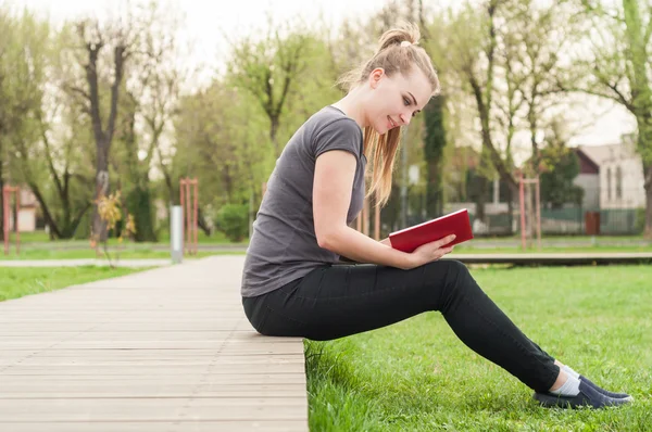 Felice giovane ragazza rilassante nel parco e la lettura — Foto Stock