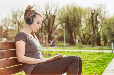 Parkta bir kitap okuma kulaklık ile güzel kadın