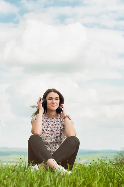 Mladá žena, poslech hudby a relaxační venku na louce — Stock fotografie