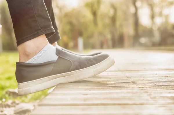 Closeup of female's feet wearing casual shoes sitting outside — Stock Photo, Image