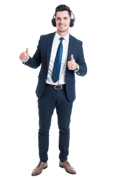 Cheerful smiling businessman listening music and thumb up — Stock Photo, Image