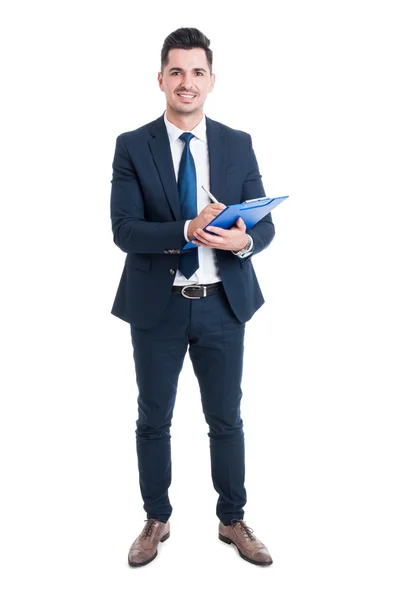 Corpo inteiro de empresário sorridente segurando prancheta azul e escritura — Fotografia de Stock