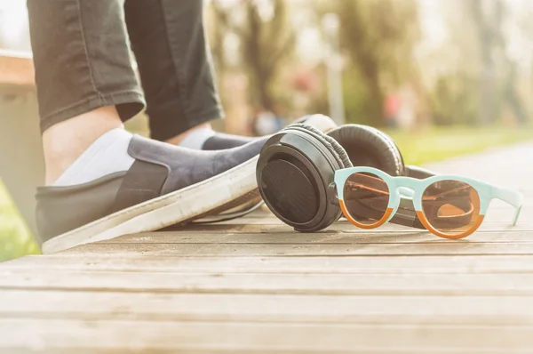 Woman legs in closeup standing next to headphones and sunglasses — Stock Photo, Image
