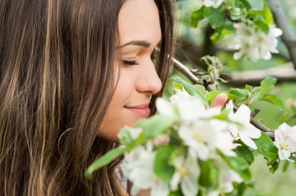 Nahaufnahme Porträt einer glücklichen Frau, die im blühenden Obstgarten steht — Stockfoto