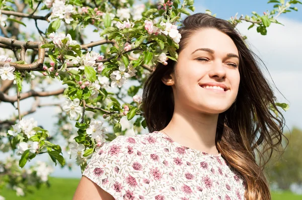 Portrét krásné usmívající se žena sedí v rozkvetlé zahradě — Stock fotografie