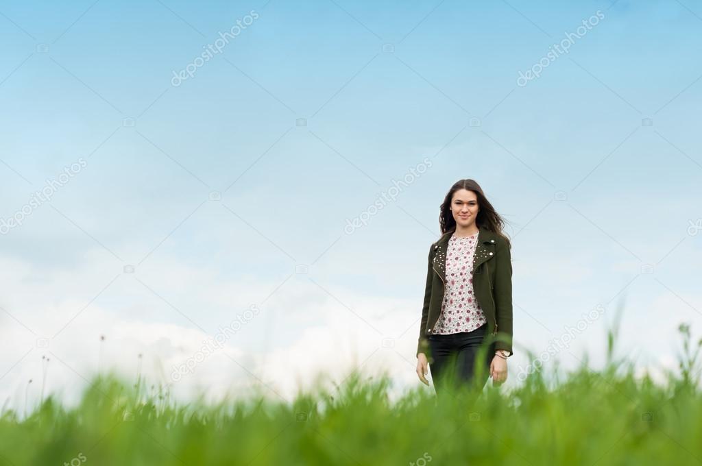 Cheerful young woman standing outside on green meadow