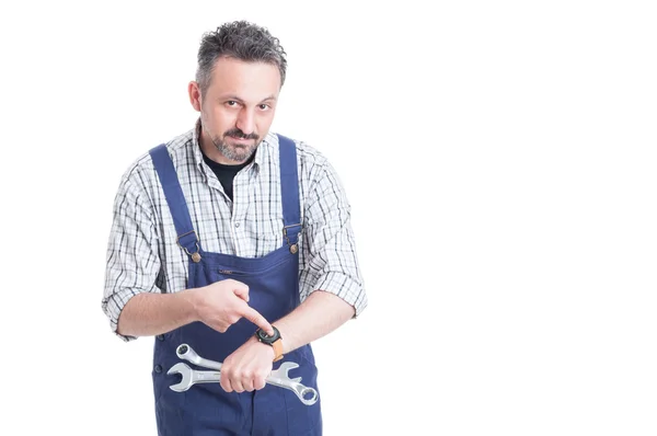 Aantrekkelijke jonge reparateur wijzende vinger op zijn horloge — Stockfoto