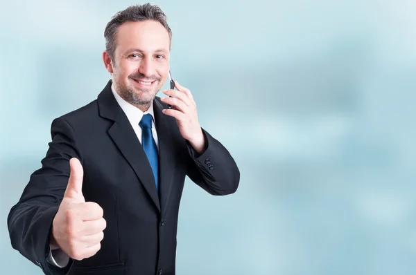 Trustworthy handsome manager talking on cellphone and showing th — Stock Photo, Image