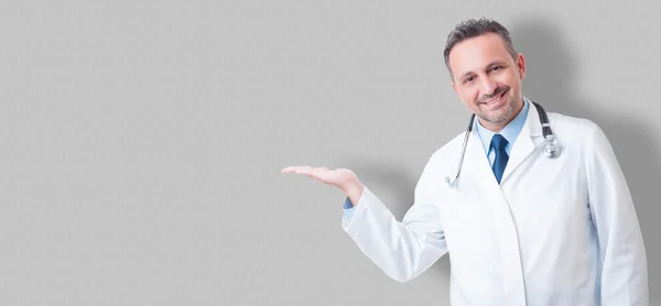 Junger Arzt lächelt und präsentiert etwas mit seinem h — Stockfoto