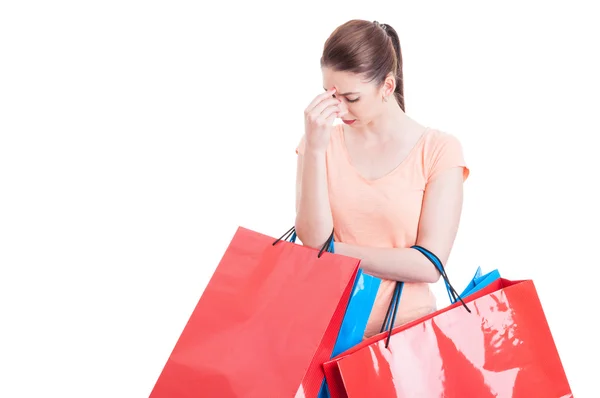 Mujer joven sosteniendo bolsas de compras con dolor de cabeza o siendo stres —  Fotos de Stock